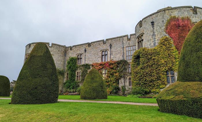 The East Front of Chirk Castle from the gardens, showing autumn colour in the leaves of the climbing plants on the castle walls and yew topiary in the